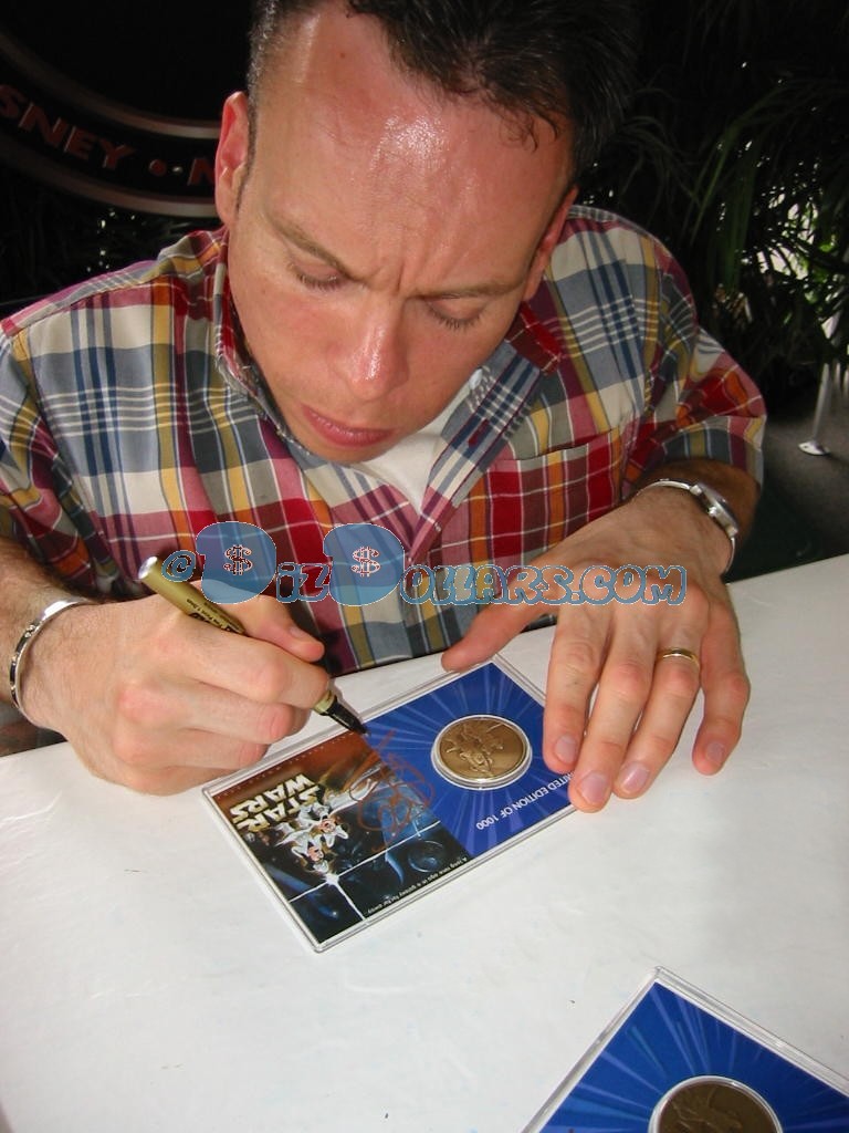 Warwick Davis (Wicket) signing and dating this Star Wars Weekends bronze Limited Edition 1000 coin 6-6-04 You will receive this photo with this coin ~ © Dizdollars.com